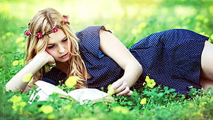 man laying on grass field reading a book