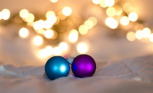 macro photography of two purple and teal baubles on white surface