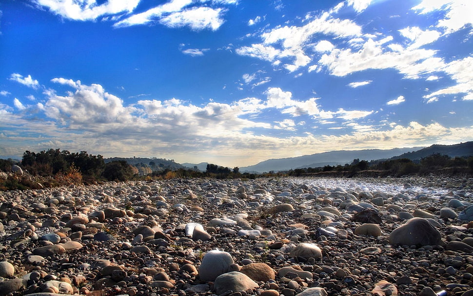 stones near mountain under white clouds HD wallpaper