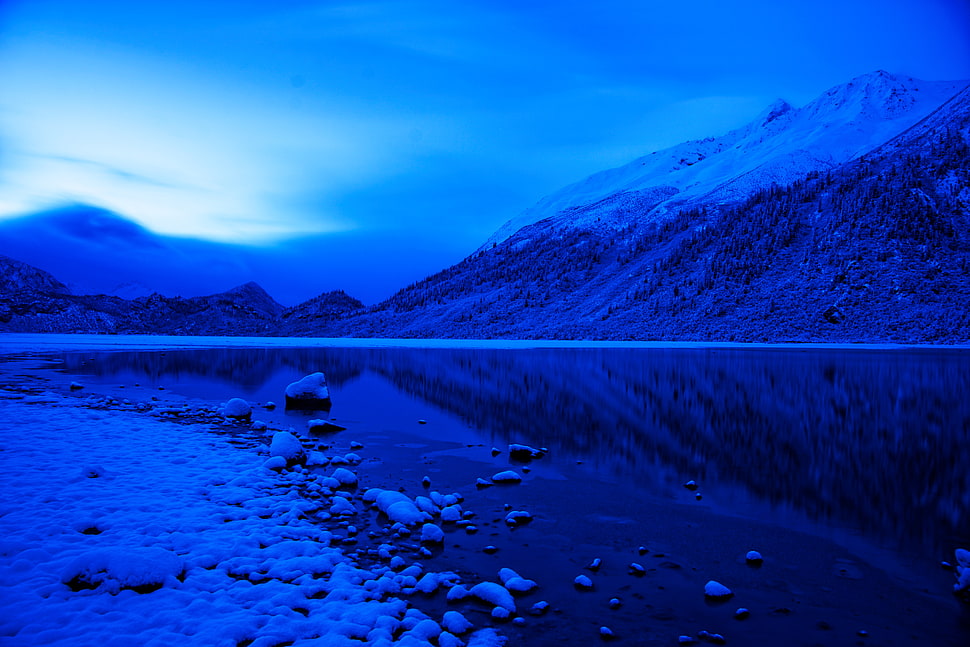 body of water beside snow covered mountains HD wallpaper