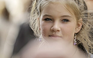girl wearing gold-colored earrings smirking
