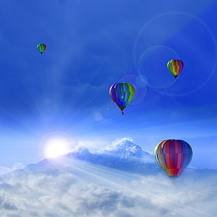 four hot air balloons through sky above of snow cone mountain