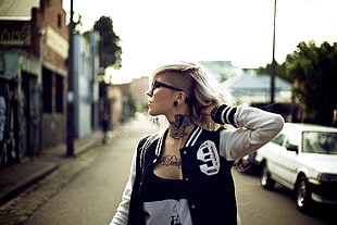 woman wearing black and white scoop neck top and black and white letterman jacket with hand behind neck