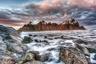 cascading photo of sea waves with brown mountain background, iceland