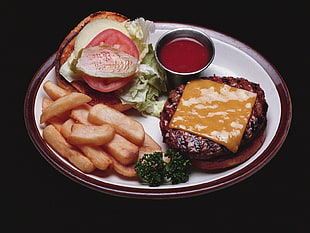 burger, fries, and red sauce on white and brown ceramic plate