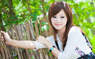 woman in white shirt holding brown fence during daytime