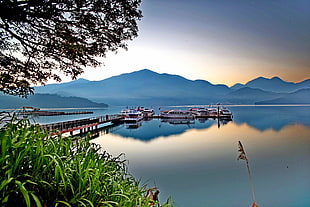 boats near dock with mountains, sun moon lake, taiwan