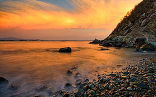 photography of seashore beside mountain during golden hour