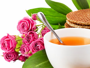 close up photography of cup of tea near bouquet of pink roses