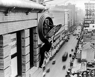 grayscale photograph of man standing on side building, architecture, monochrome, building, Harold LLoyd