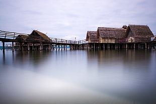 shacks on body of water under cloudy sky