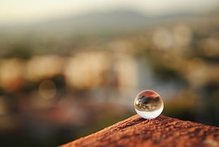 clear glass ball on brown surface focus shot