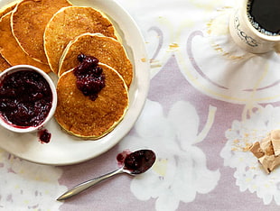 pancakes with berry spread on ceramic plate on floral surface