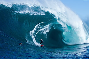 man surfs on big wave during daytime