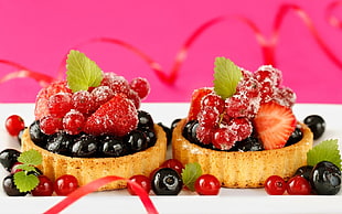 two tarts covered with assorted berries