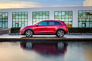 red Hyundai Tucson park beside body of water and building