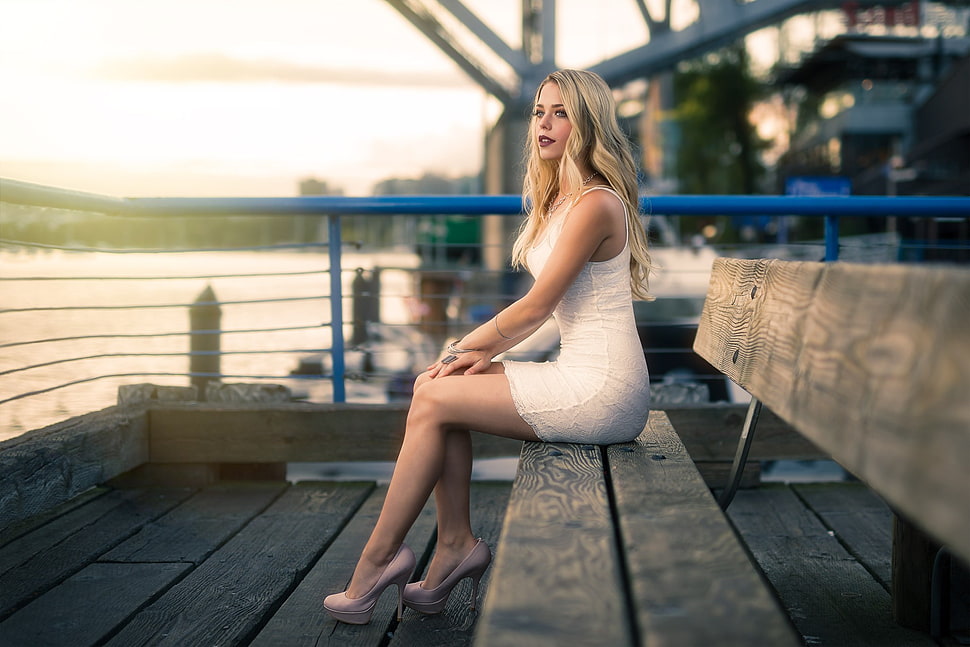woman wearing white sleeveless dress sitting on bench near body of water HD wallpaper