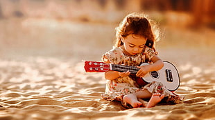 focus photography of girl holding guitar