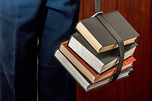 photography of four assorted books tied with black leather belt