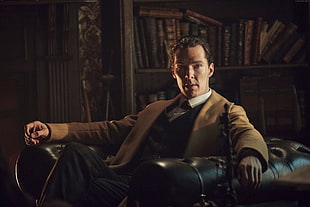 man wearing brown coat sitting on black leather armchair inside room