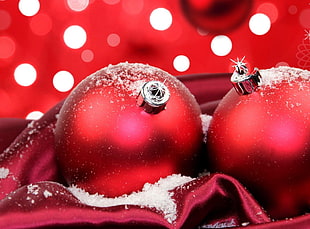 macro photography of two red baubles with snow