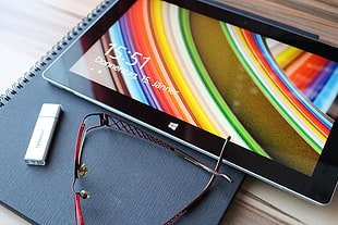 close up of windows tablet on notebook near eyeglasses and flash drive