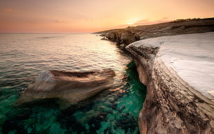 photo of body of water with rock formation HD wallpaper