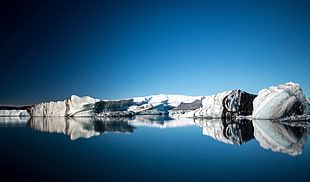 reflective photography of iceberg under blue sky