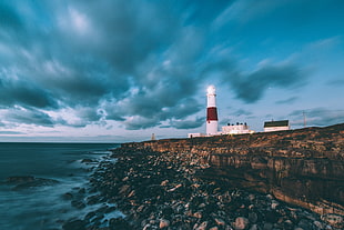 landscape photography of white lighthouse in front of body of water