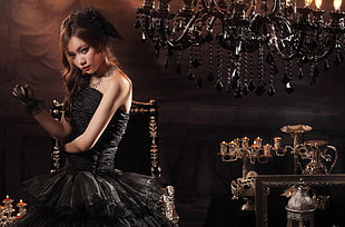woman with black strapless fit and flare dress next to candle holder and chandelier
