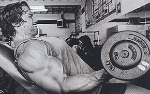grayscale photo of man on bench press carrying barbell