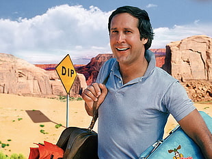 man wearing blue polo shirt standing near brown rock formation HD wallpaper