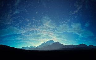 silhouette photo of mountains under blue sky and white clouds