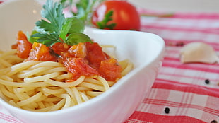pasta with tomato and parsley toppings in white bowl