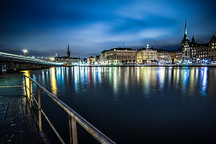 photography of brown concrete buildings near body of water during night time, stockholm HD wallpaper