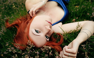 woman wearing blue spaghetti strap top lying on grass closeup photography