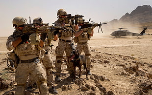 four soldiers holding assault rifles with scopes near gray helicopter HD wallpaper
