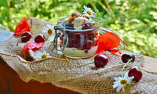 clear glass jar filled with cream topped with chips and cherries