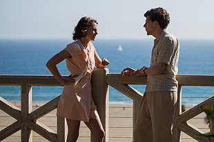 man and woman beside ocean talking during daytime