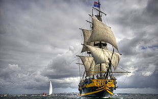 yellow and black ship sailing under cloudy sky