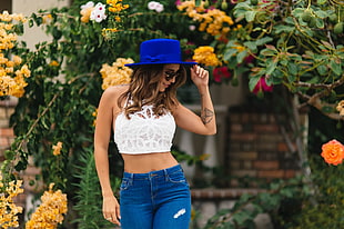 woman in white crop top and blue denim bottoms standing near flowers HD wallpaper