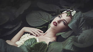 photo of woman in beaded beige strapless dress laying on plants
