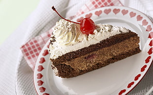 brown and white cake slice with cherry fruit garnish