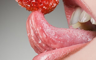 person licking red strawberry