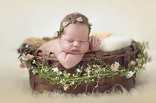 baby with pink rose headdress sleeping on a basket
