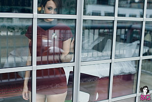woman wearing red and black mini dress standing beside the window