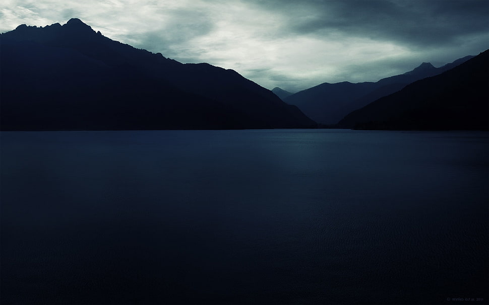body of water and mountain under black sky HD wallpaper