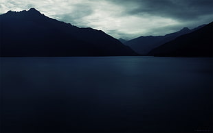 body of water and mountain under black sky