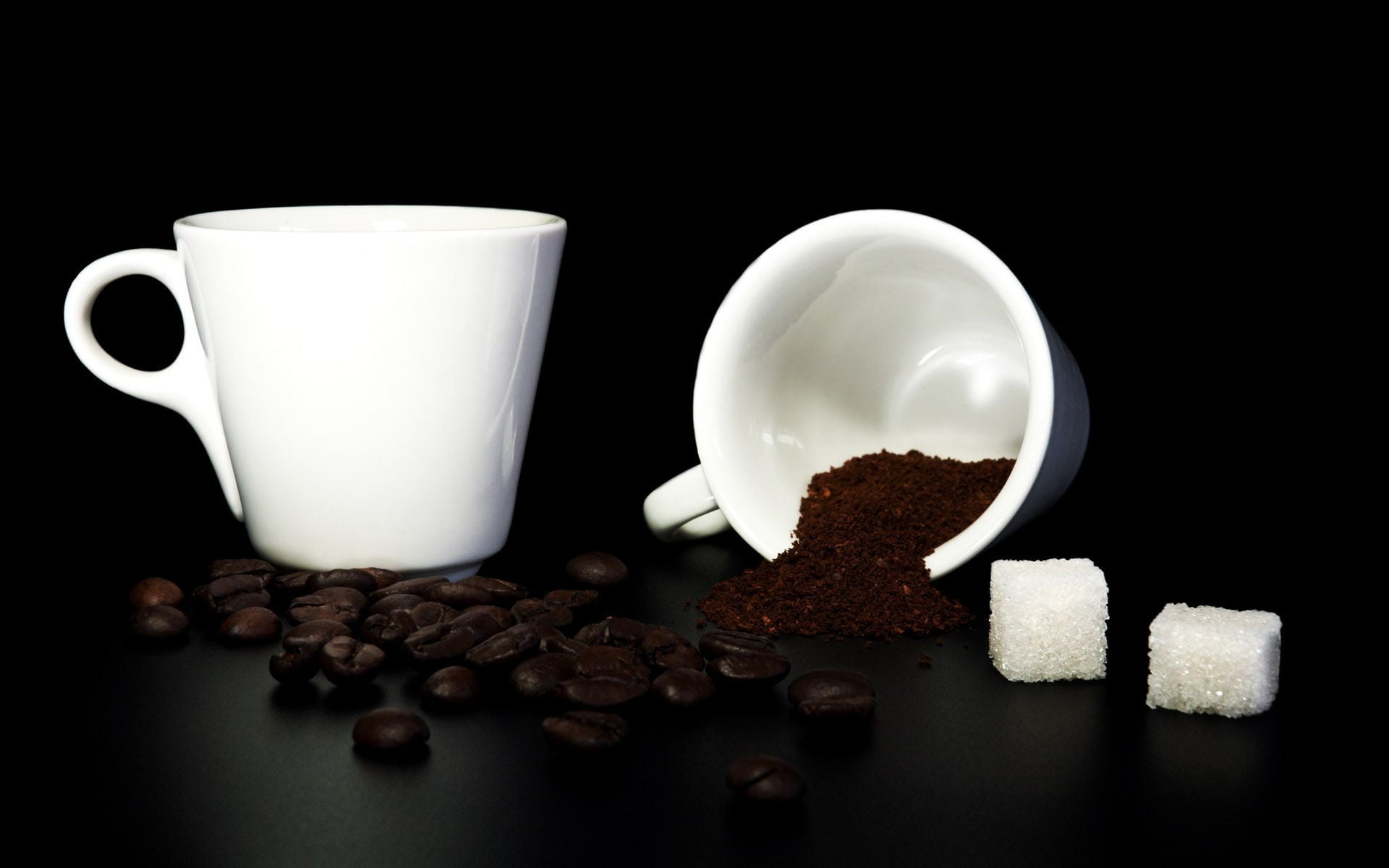 two white ceramic mugs with coffee beans and sugar cubes