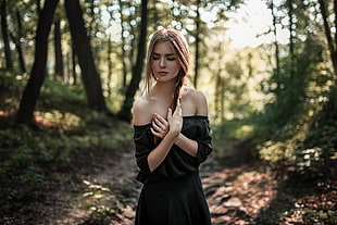 woman wearing black off-shoulder quarter-sleeved top standing in forest